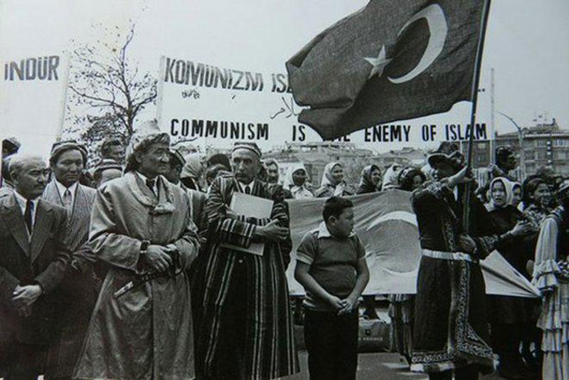 Alptekin, tenant un livre, dirige une manifestation de soutien au séparatisme du Turkestan oriental en 1966. Alptekin se tient devant une banderole qui dit: «Le communisme est l'ennemi de l'islam». 