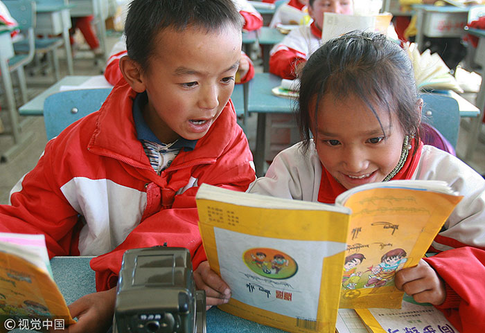 Des élèves lisent un manuel scolaire tibétain dans une école de Shigatse, le 19 octobre 2009 / VCG Photo
