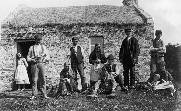 Vers 1900 : Des habitants de Gweedore, dans le comté de Donegal, devant leur petite ferme au toit de chaume. On remarquera les pieds nus d’une partie de la famille. Vers 1900 : Des habitants de Gweedore, dans le comté de Donegal, devant leur petite ferme au toit de chaume. On remarquera les pieds nus d’une partie de la famille.