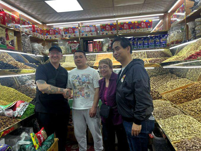 Arjae Red, Sara Flounders et Lee Siu Hin, à droite, avec le vendeur de fruits et de noix Nazar, à Urumqi, mai 2023.