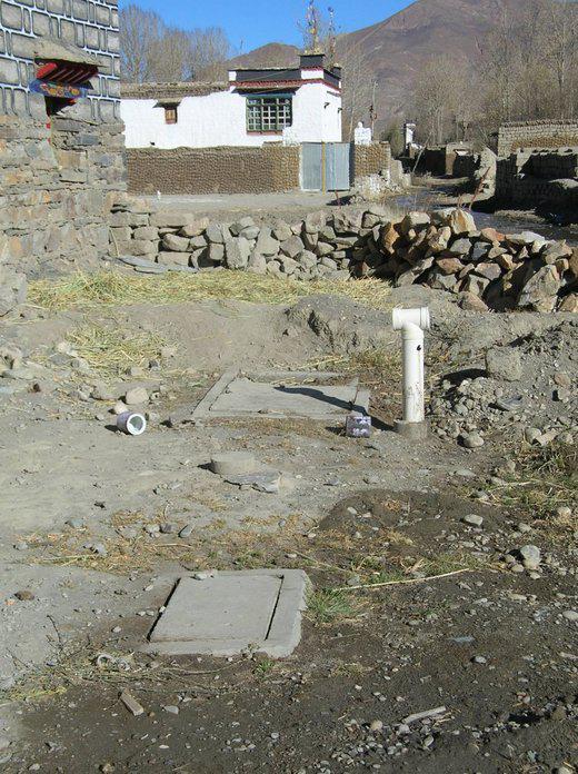 puits de méthane avec les deux couvercles. Au loin, collées sur le mur, des bouses de yack sèchent au soleil. (photo JPDes., 2008)