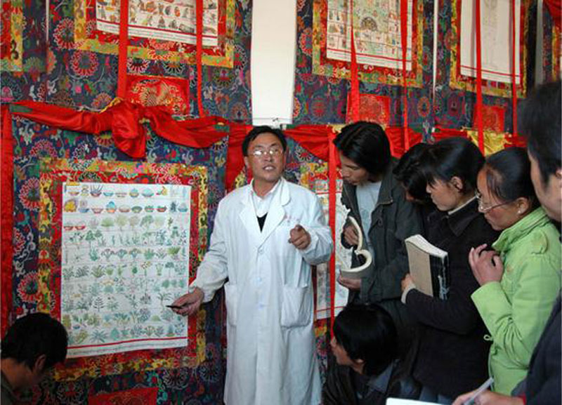 Sonam Tsering, un Manpa (médecin traditionnel), présente aux étudiants les herbes médicinales destinées au bain Lum, tel qu’il est consigné dans le thangka médical Gyud zhi (Les Quatre Tantras) (*)